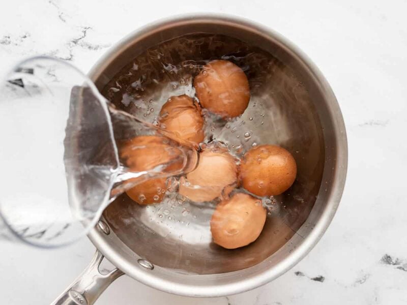 Water being poured into a pot with eggs