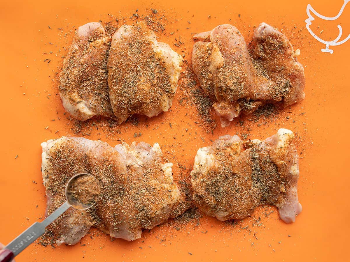 seasoned chicken thighs on a cutting board.