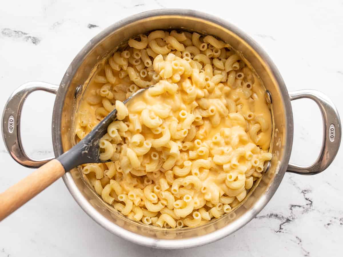 Cooked macaroni being stirred into the cheese sauce
