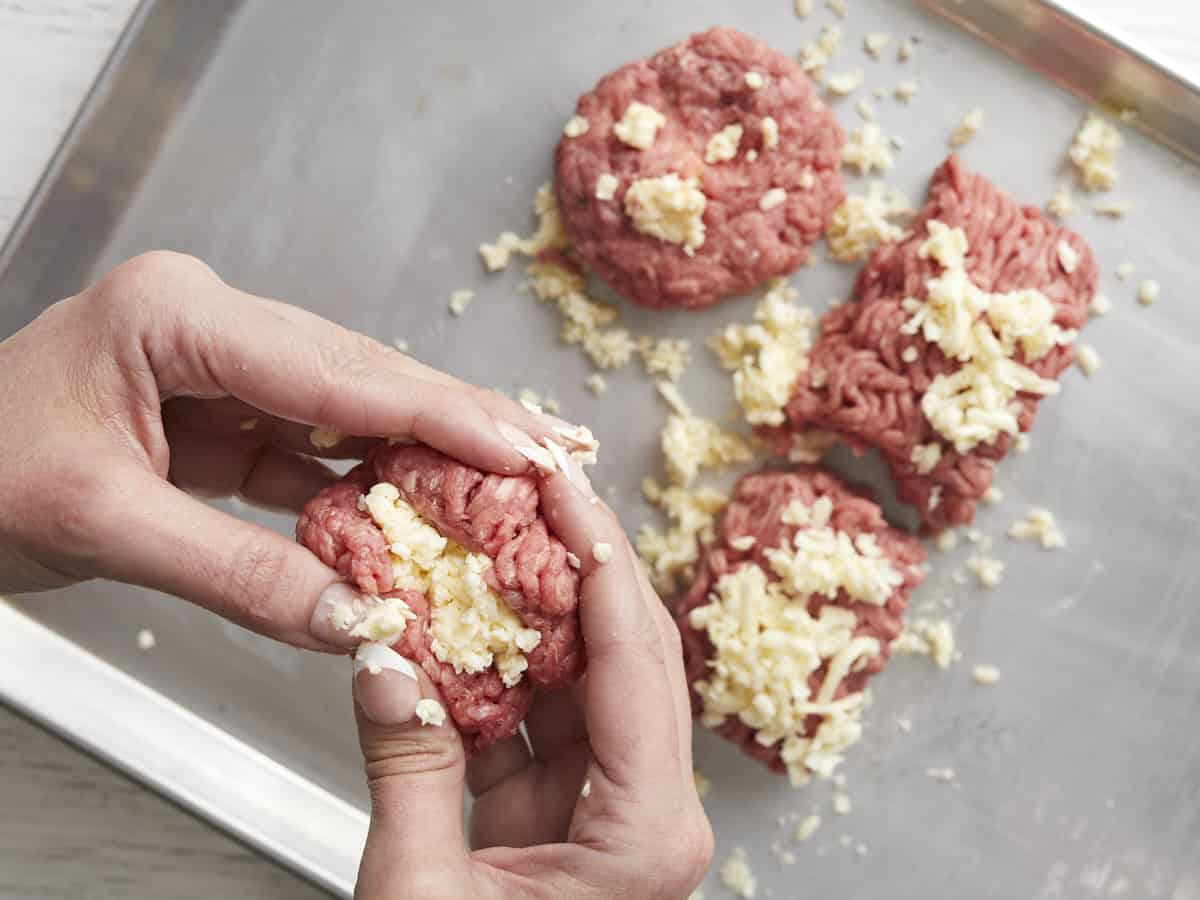 Overhead shot of frozen, grated butter being tucked into a ball of beef.