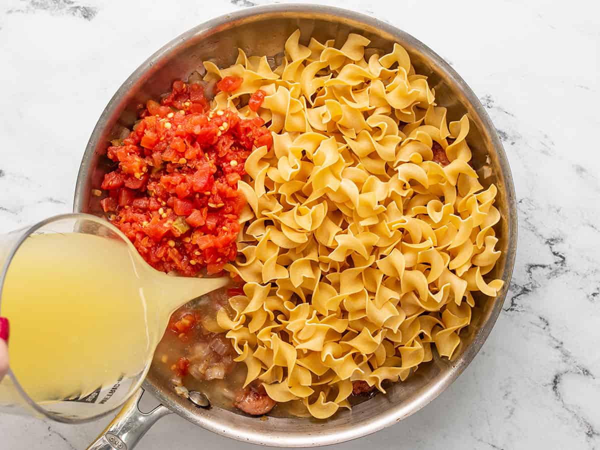Pasta, tomatoes, and broth added to the skillet.