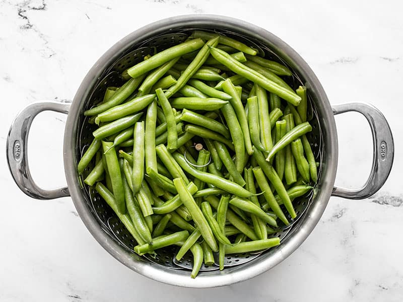 Fresh green beans in the steam basket in the pot, uncooked