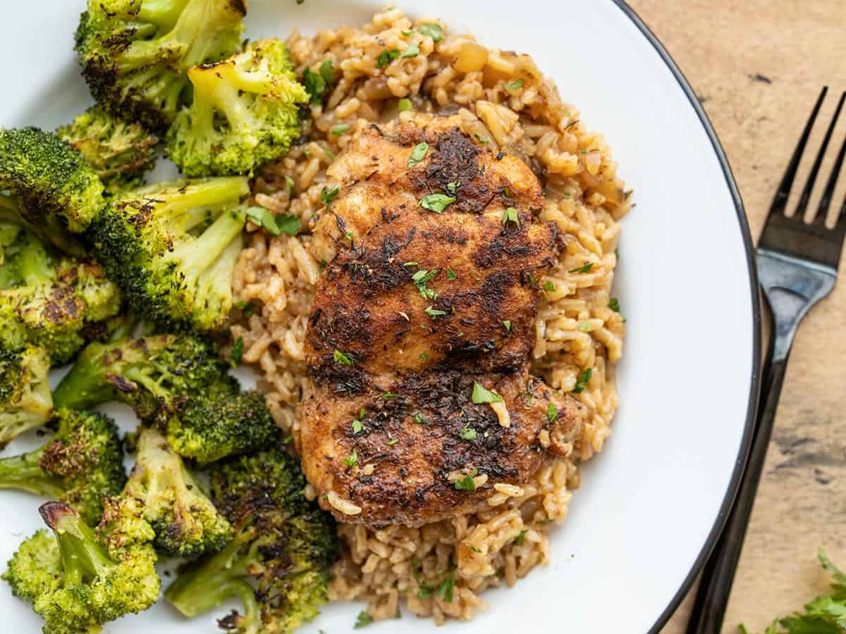 Chicken and rice on a plate with roasted broccoli.