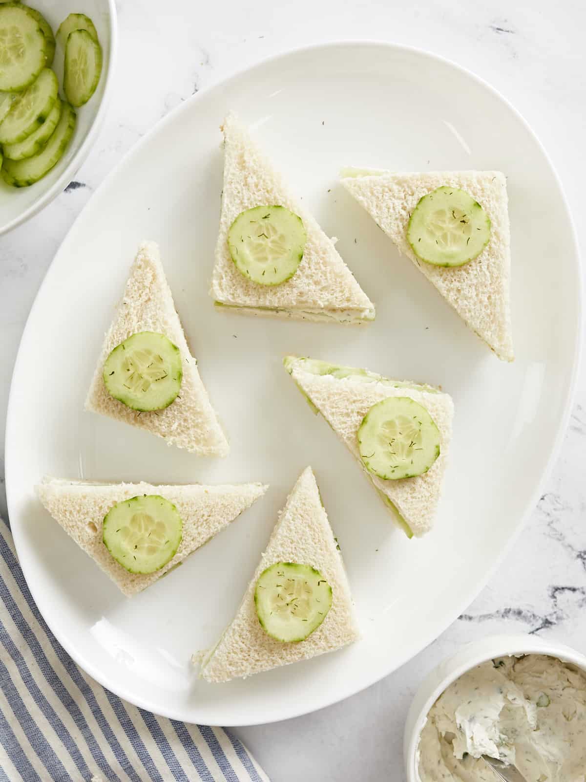 Overhead view of cucumber sandwiches on a platter.