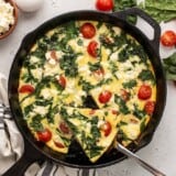 Sliced frittata in the skillet, one slice being lifted.