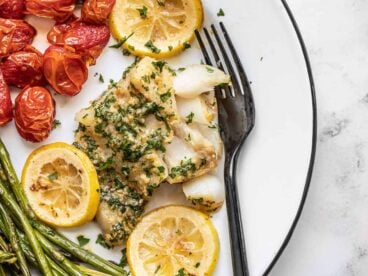flaked garlic butter baked cod on a plate with a fork