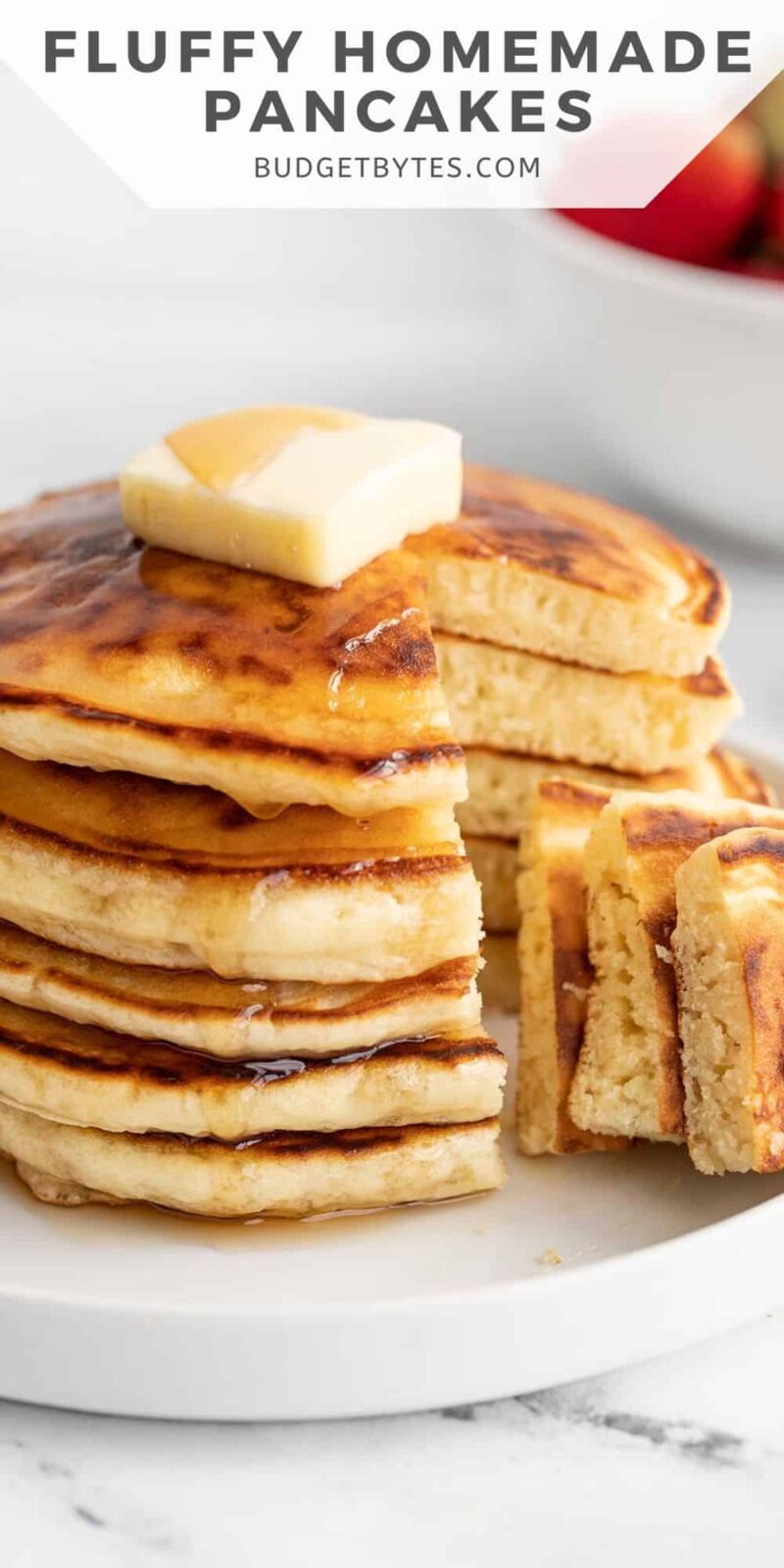 Side view of a sliced stack of pancakes with butter and syrup.