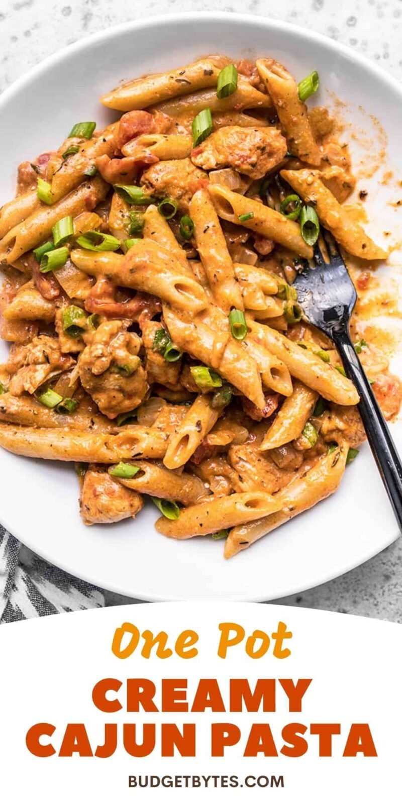 Close up of a bowl of creamy cajun chicken pasta, title text at the bottom