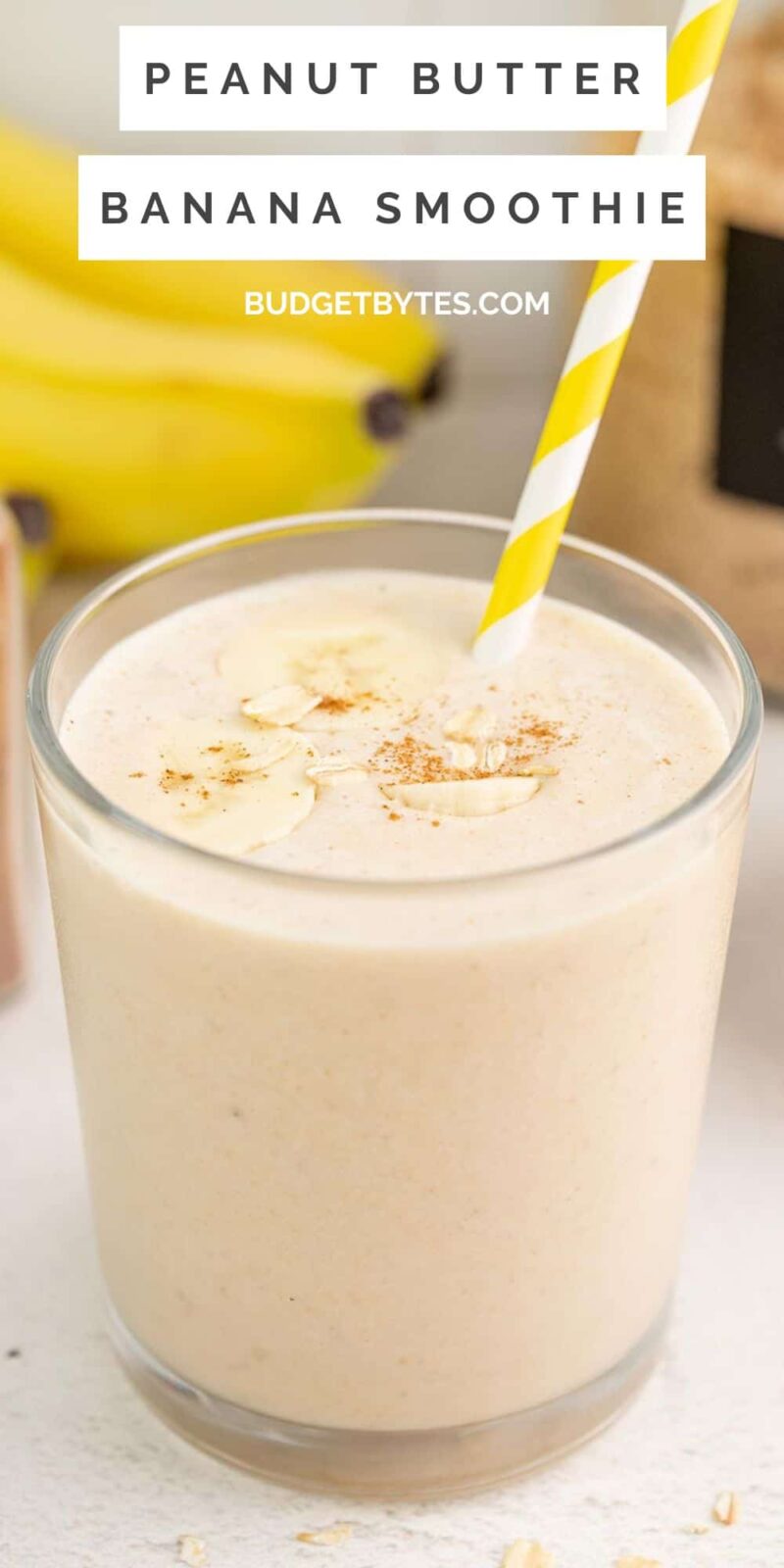 Side view of a glass full of peanut butter banana smoothie with a strw.