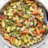 Easy pesto chicken and vegetables in a skillet with a spatula