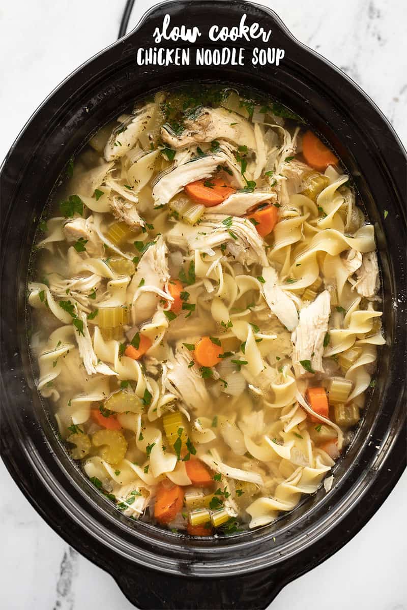 Overhead view of chicken noodle soup in a slow cooker, title text at the top