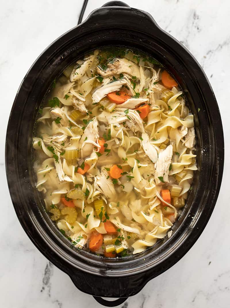 Overhead view of a slow cooker containing freshly cooked homemade chicken noodle soup