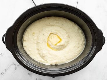 Overhead view of mashed potatoes in the slow cooker with melted butter