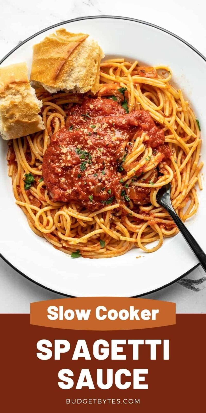 A plate of pasta with spaghetti sauce and bread on the side