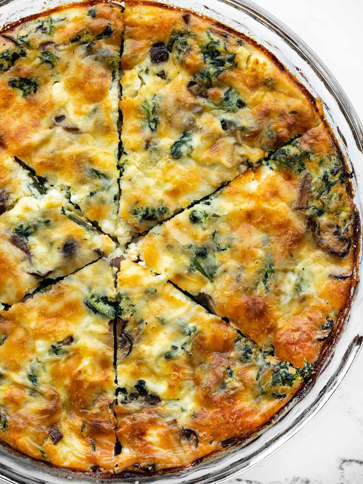Close up overhead view of a spinach and mushroom crustless quiche in a pie dish