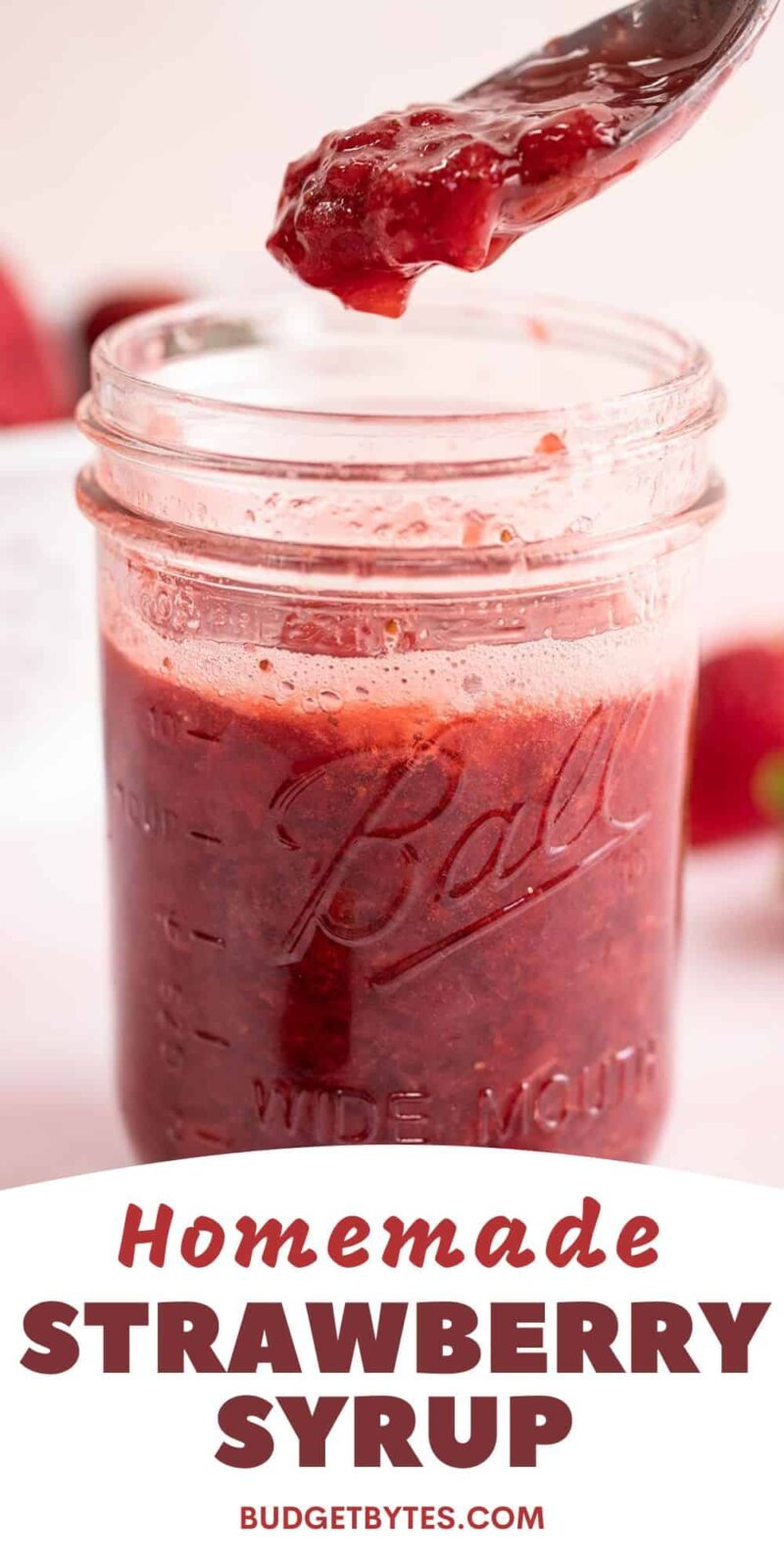 Strawberry syrup dripping off a spoon into a mason jar.
