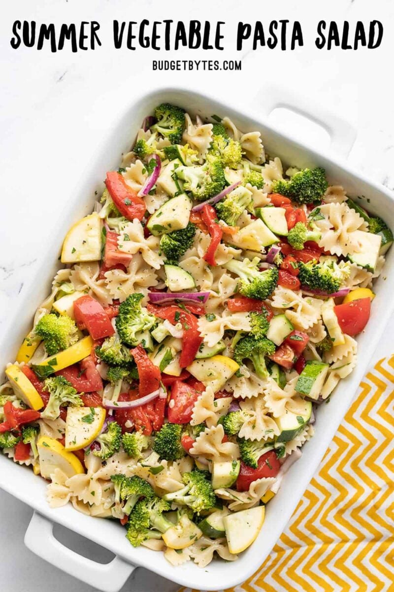 summer vegetable pasta salad in a rectangular casserole dish with title text at the top